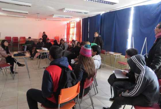 La imagen muestra el desarrollo de un taller de teatro realizado en el liceo Horacio Aravena Andaur. Participan de este encuentro la directora de la Compañía de Teatro KIMVN, Paula González, un grupo de estudiantes y el orientador del establecimiento, Salvador Varas.