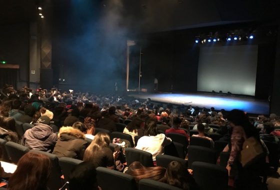 La imagen muestra el escenario del Teatro UC con las butacas llenas de estudiantes de liceos PACE UC esperando la función de la obra Mocha Dick en mayo 2019.