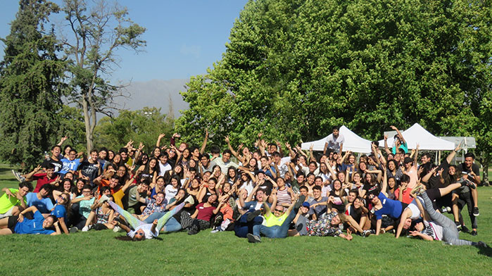 Fotografía de una foto de cientos de jóvenes levantando las manos sentados en explanada de pasto
