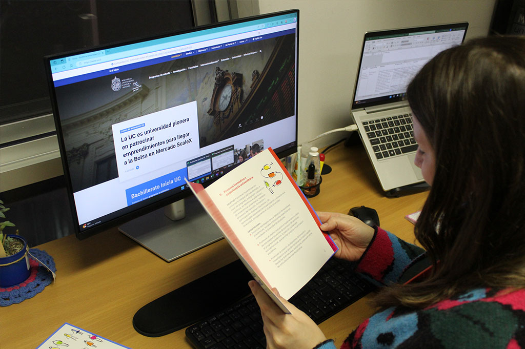 Fotografía de una persona leyendo la Política de Inclusión UC actualizada frente a un computador donde aparece la web oficial de la Universidad Católica
