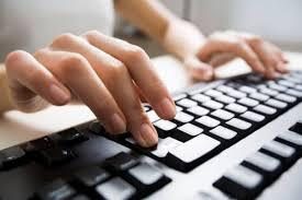 En la imagen se ve a una persona escribiendo en un computador de escritorio. Sólo se visualizan las manos de la persona sobre un teclado blanco.