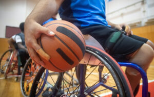 Foto de una persona jugando ásquetbol adaptado en silla de ruedas