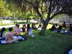 Estudiantes de primer año sentados en pasto sobre mantas conversando con mascarilla.
