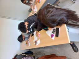 Estudiantes escribiendo con distintos materiales, sentados en sala de clases