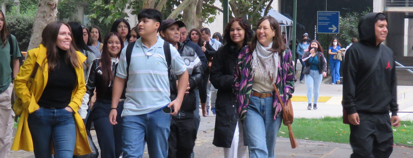 Fotografía de alumnos escolares y docentes caminando y sonriendo en un lugar exterior