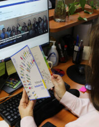 Fotografía de una persona leyendo la Política de Inclusión UC actualizada frente a un computador donde aparece la web de la Dirección de Inclusión UC